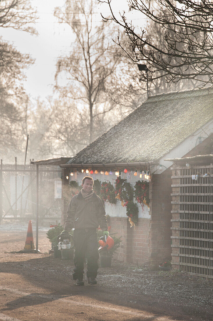 Mann steht mit Helm vor Hawkwell Weihnachtsbaum-Farm-Shop Essex England UK (Model Released)