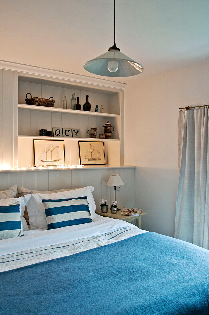 Maritimes Schlafzimmer mit blauer Decke und eingelassenen Regalen in einem Haus in Crantock, Cornwall, England UK