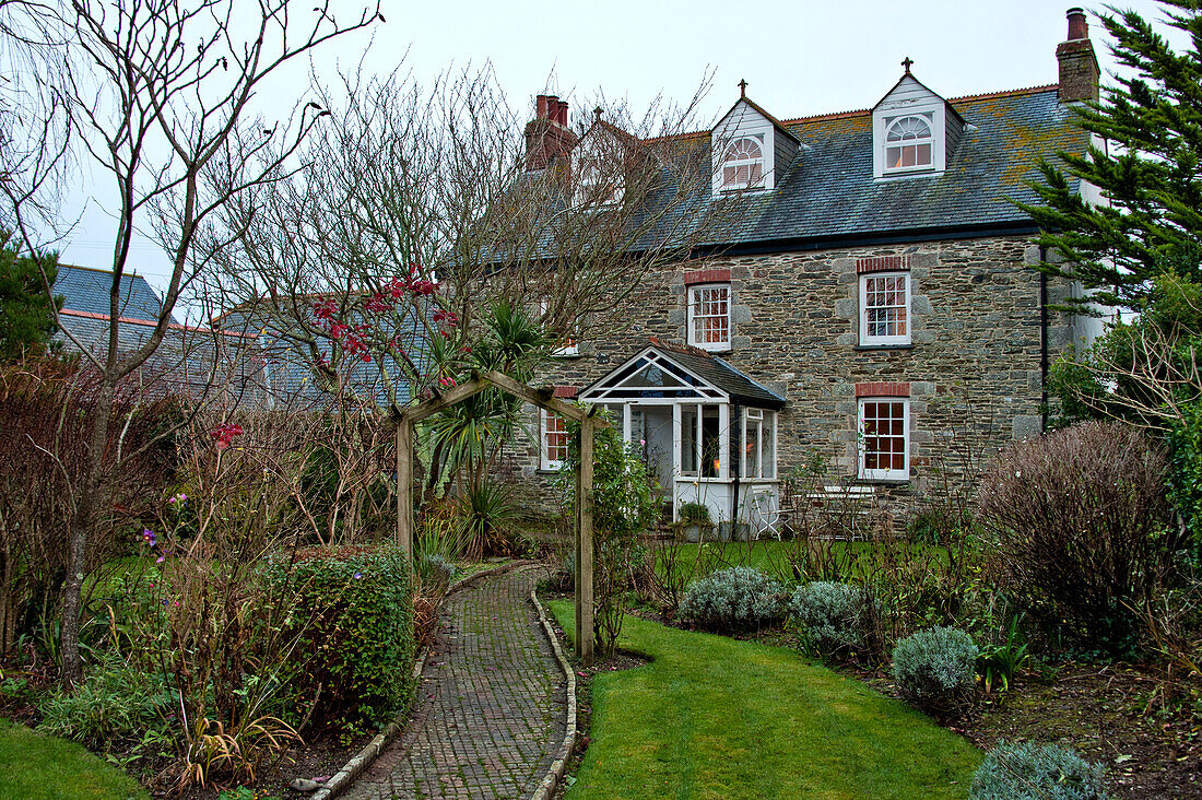 Brick path with pergola in front garden of stone farmhouse in Crantock Cornwall England UK