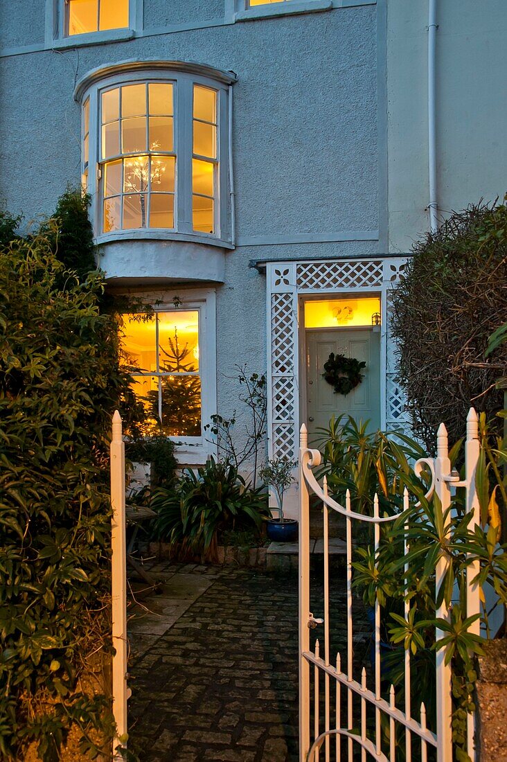 Offenes Tor und beleuchtete Fenster eines mit Kieselstein gepflasterten Reihenhauses in Penzance Cornwall England UK