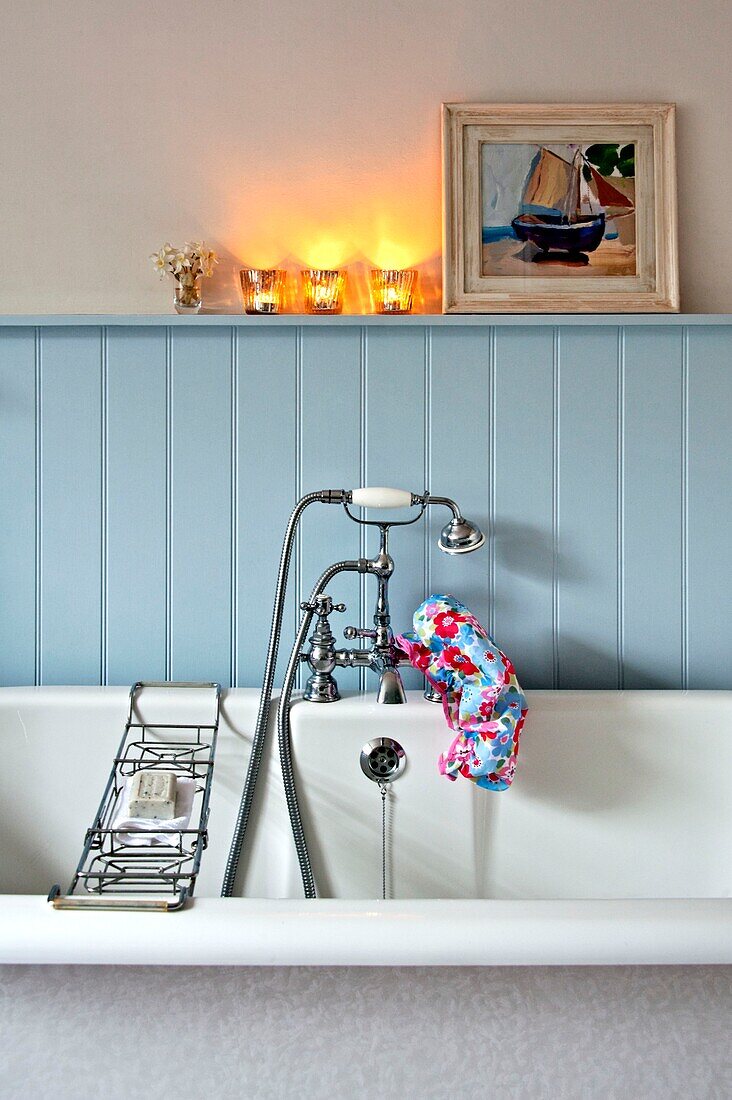 Lit tealights above light blue panelled bath with shower fitting and rack in Penzance family home Cornwall England UK
