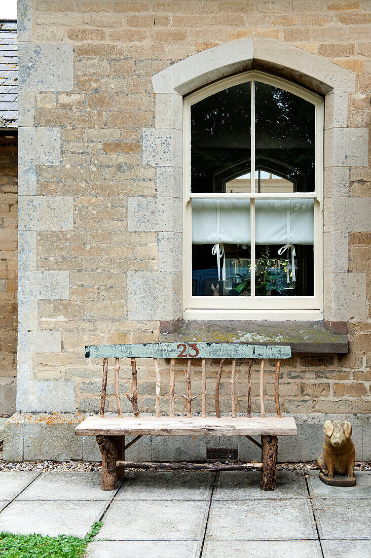 Weathered bench seat below window of old stone Stamford home Lincolnshire England UK