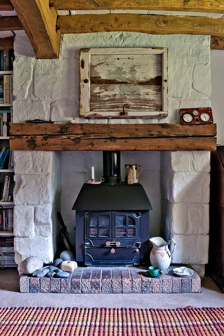 Woodburning stove in whitewashed fireplace of Cambridge cottage England UK