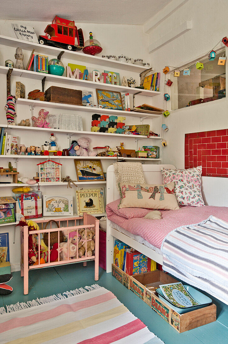 Einzelbett mit Spielzeug auf offenem Regal in einem Cottage in Cambridge (England)