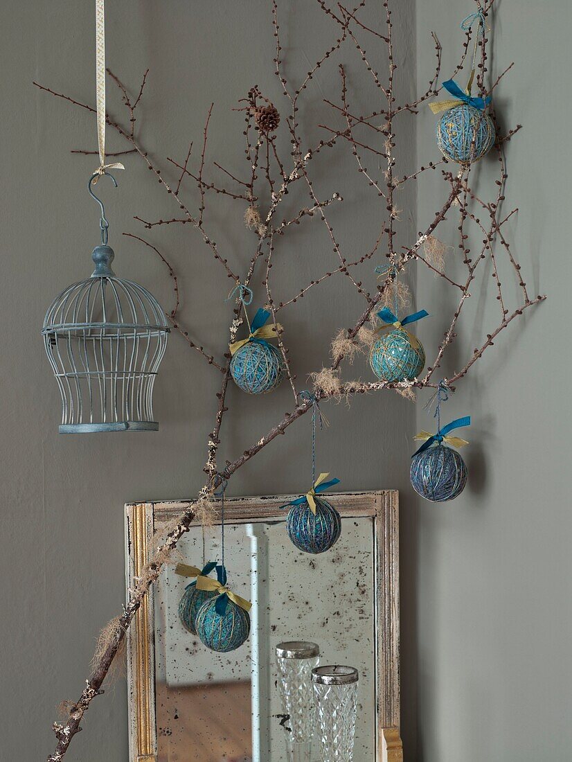 Handmade Christmas baubles hang above vintage mirror with birdcage in London home England UK