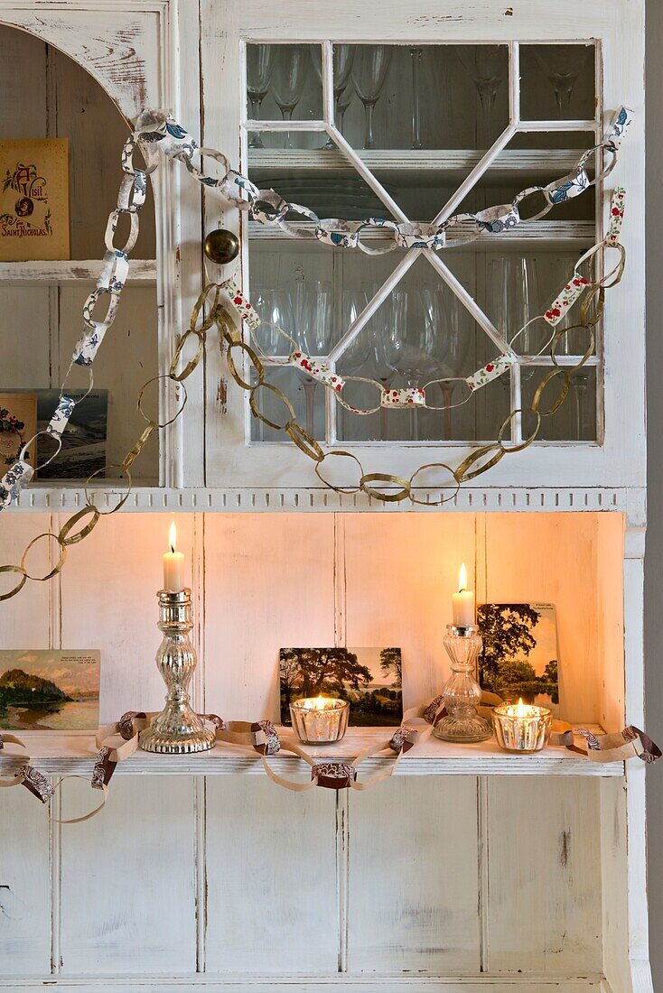 Lit candles and paper chains on painted dresser in London home England UK