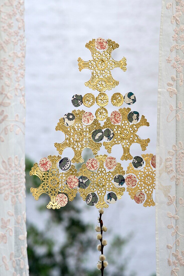 Goldene Schneeflocken-Deckchen mit Spitzenvorhängen im Fenster eines Hauses in London England UK