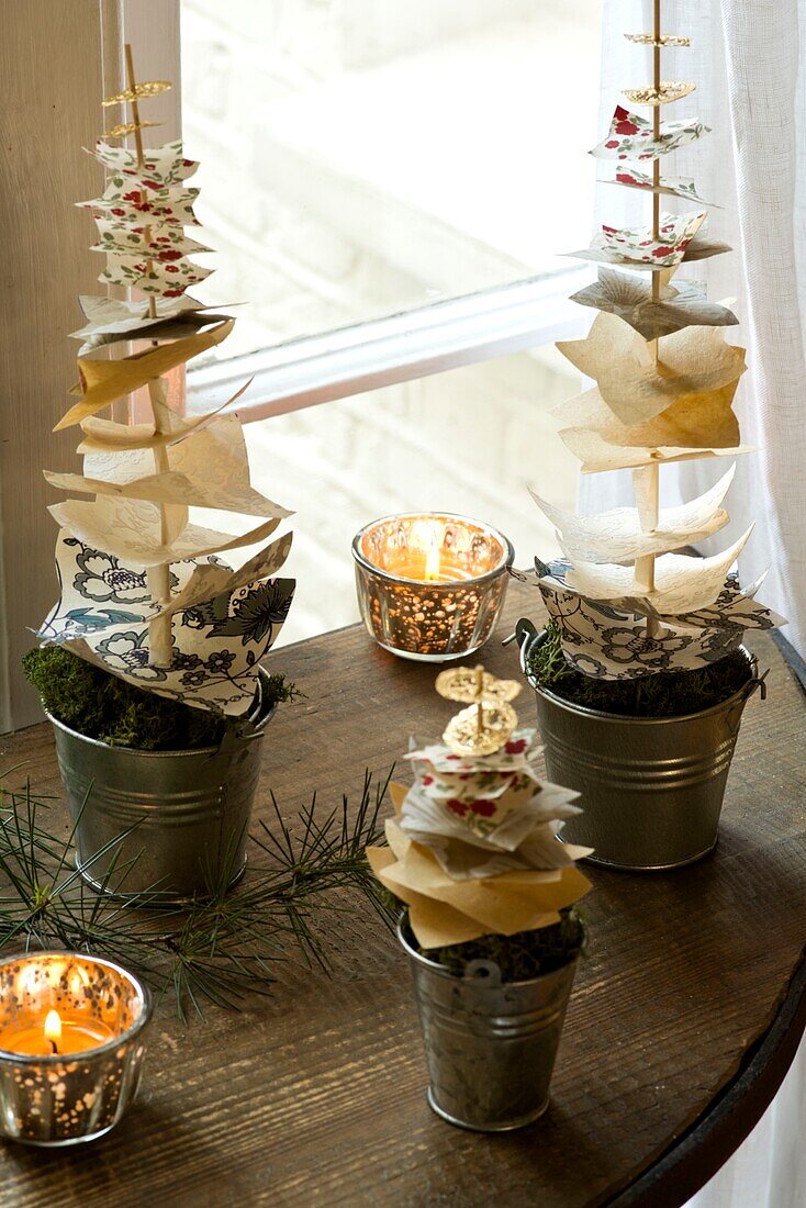Beleuchtete Teelichter mit Weihnachtsschmuck auf einem hölzernen Beistelltisch in einem Londoner Haus England UK