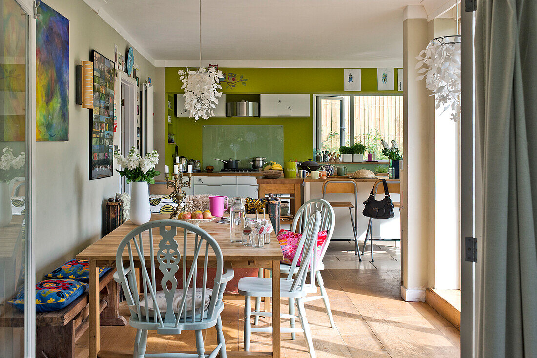 Painted chairs at wooden table in lime green open plan kitchen of East Grinstead family home West Sussex England UK