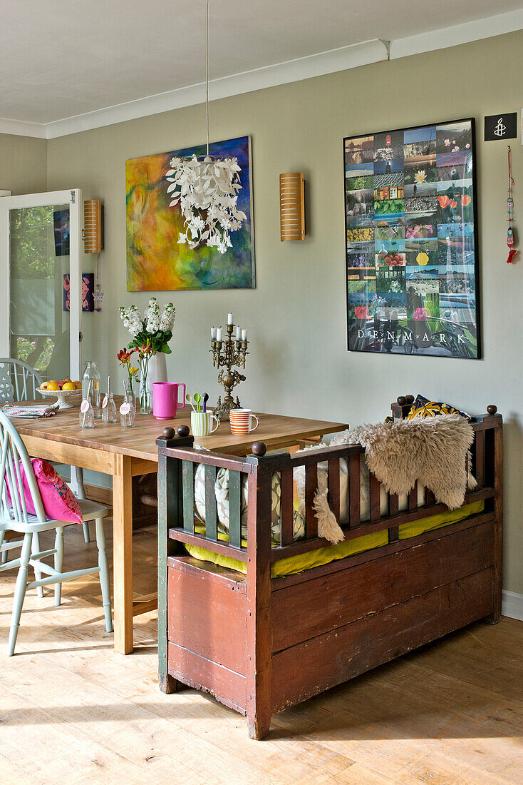 Ausrangierte Sitzbank am Küchentisch mit Kunstwerken im Haus einer Familie in East Grinstead, West Sussex, England UK