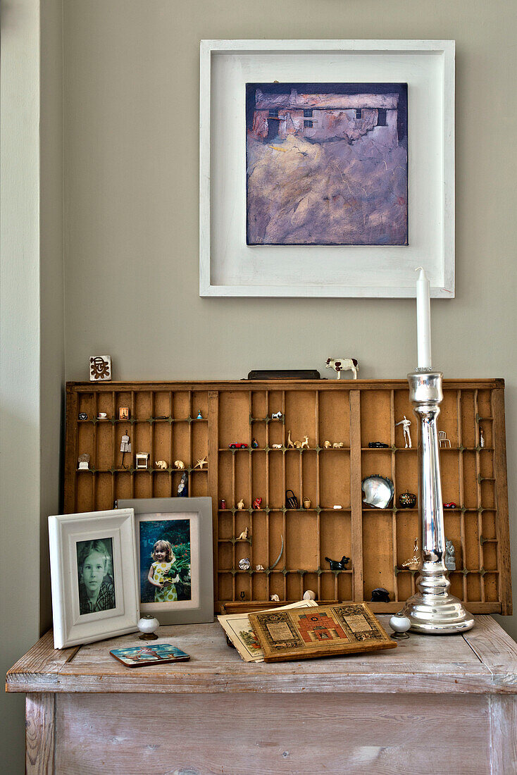 Silberner Kerzenständer und gerahmtes Kunstwerk mit Holzregalen im Haus einer Familie in East Grinstead, West Sussex, England, UK