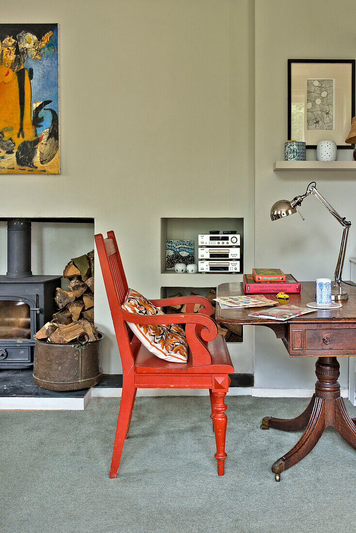 Red painted chair at desk with lamp in living room of East Grinstead family home West Sussex England UK