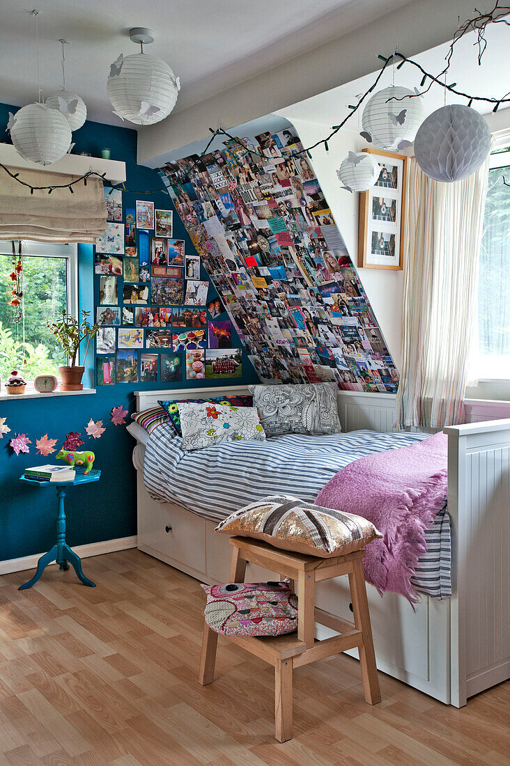 Einzelbett mit gestreifter Bettdecke am Fenster mit Fotos und Postkarten im Kinderzimmer eines Familienhauses in East Grinstead, West Sussex, England, UK