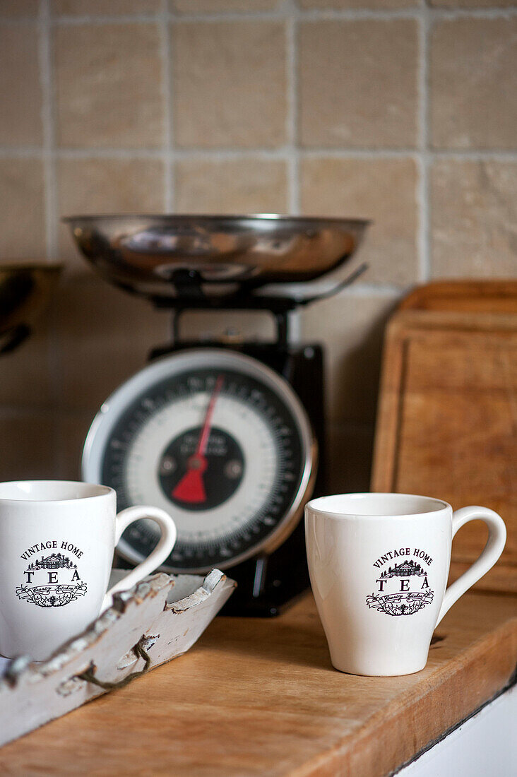 Teetassen und Küchenwaage mit Tablett auf der Arbeitsplatte in einem Haus in Stamford, Lincolnshire, England, UK