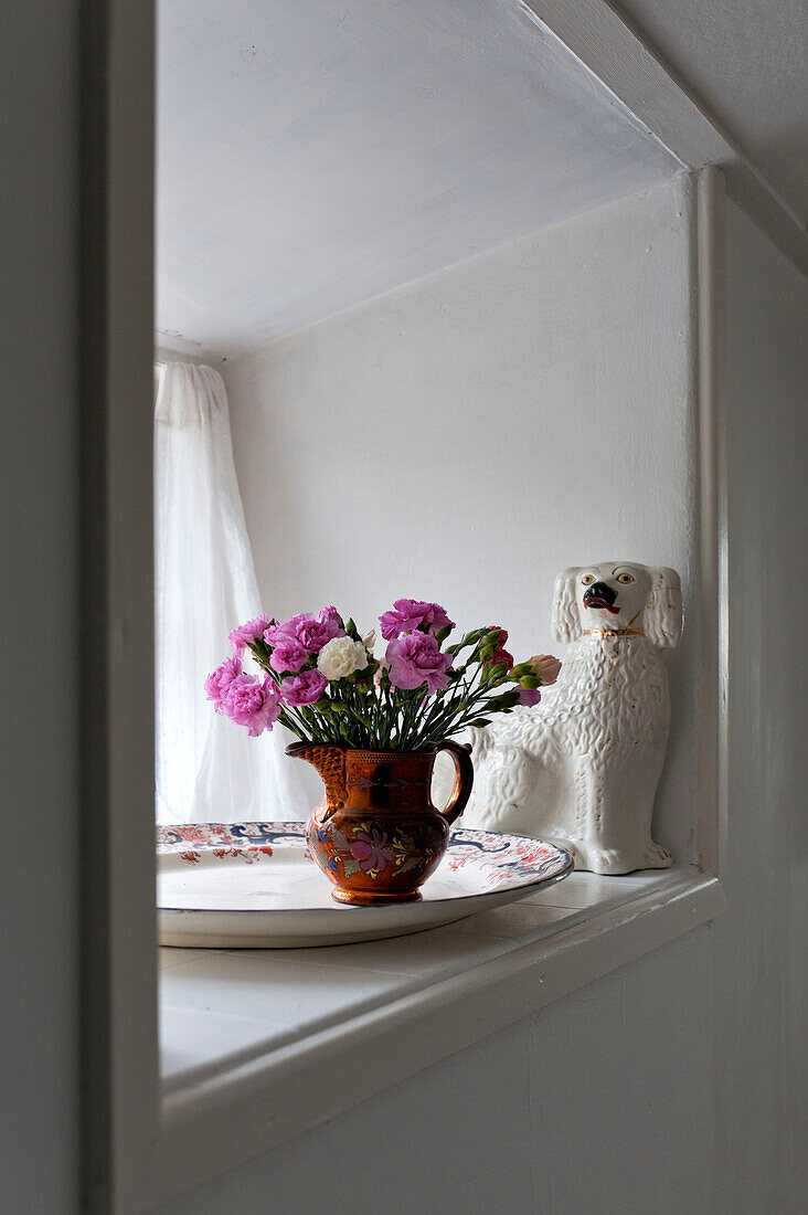 Pink carnations and dog ornament on windowsill in beach house Cornwall England UK