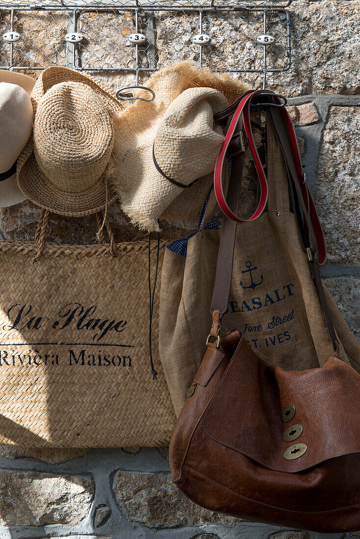 Sunhats and hessian bags on hooks in Penzance farmhouse Cornwall England UK