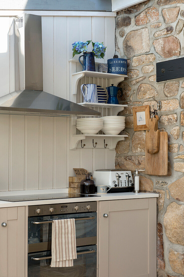 Stainless steel extractor above electric oven with exposed stone wall in Penzance farmhouse kitchen Cornwall England UK