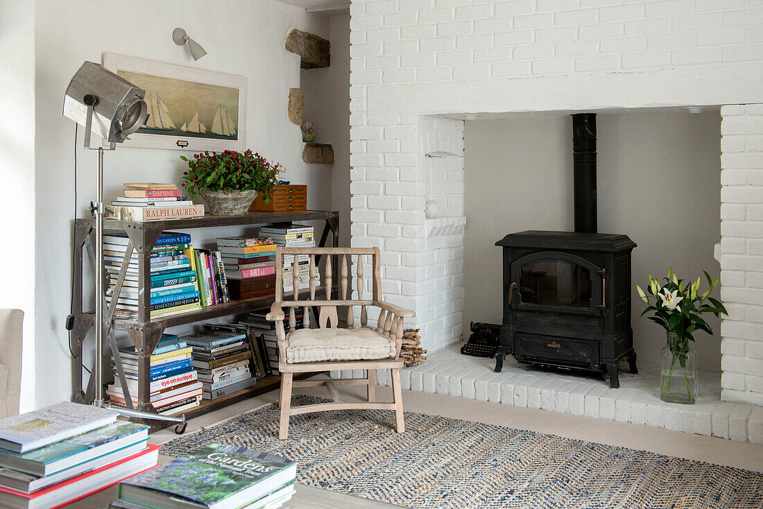 Wooden chair with bookcase and woodburner in Penzance farmhouse Cornwall England UK
