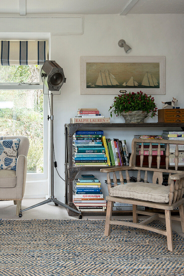 Holzstuhl mit Bücherregal in einer Ecke des Bauernhauses in Penzance, Cornwall, England, UK