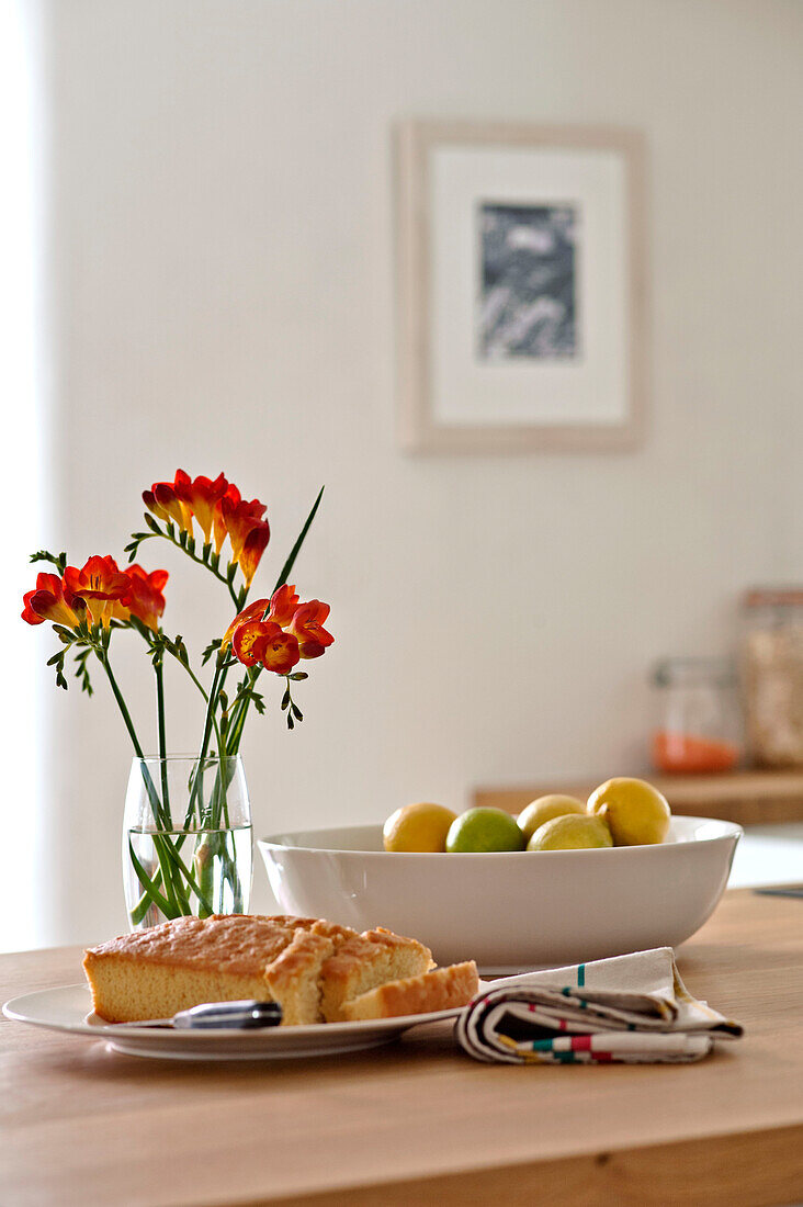 Red freesia and lemon with cake on kitchen worktop in family townhouse Cornwall England UK