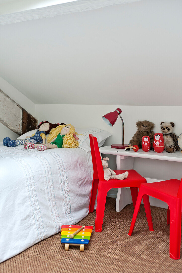 Rote Plastikstühle neben dem Kinderbett mit Stofftieren in einem Stadthaus in Cornwall, England, UK