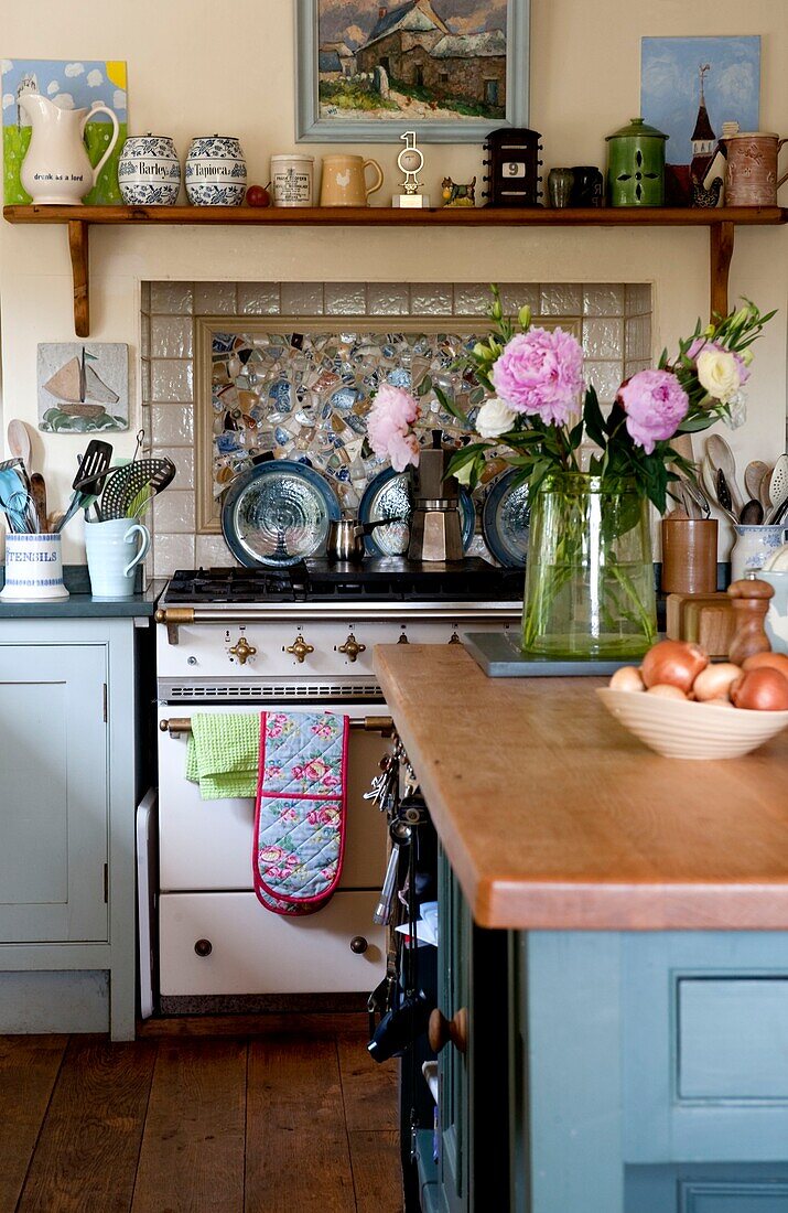 Cut flowers on wooden island unit with recessed range oven in Edworth cottage kitchen Bedfordshire England UK