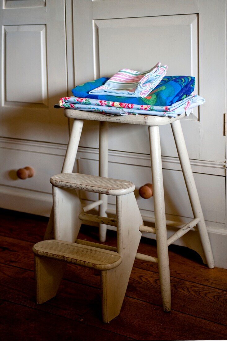 Folded blue fabrics on footstool with steps in Edworth kitchen Bedfordshire England UK