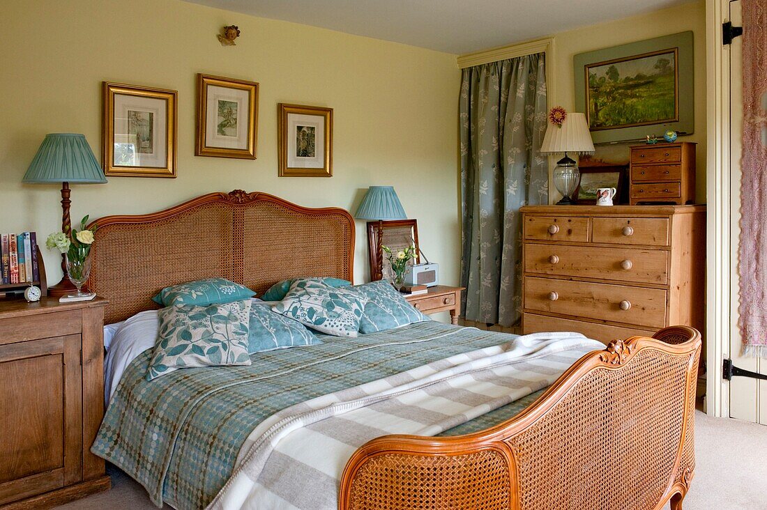 Weidenbett mit goldgerahmtem Kunstwerk und blattgemusterten Kissen im Schlafzimmer von Edworth in Bedfordshire, England UK