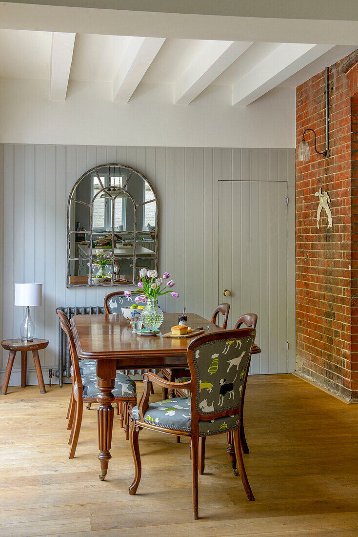 Esstisch und Stühle aus Holz mit architektonischem Spiegel und freiliegender Ziegelwand in einem Haus in Tunbridge Wells, Kent, England, UK