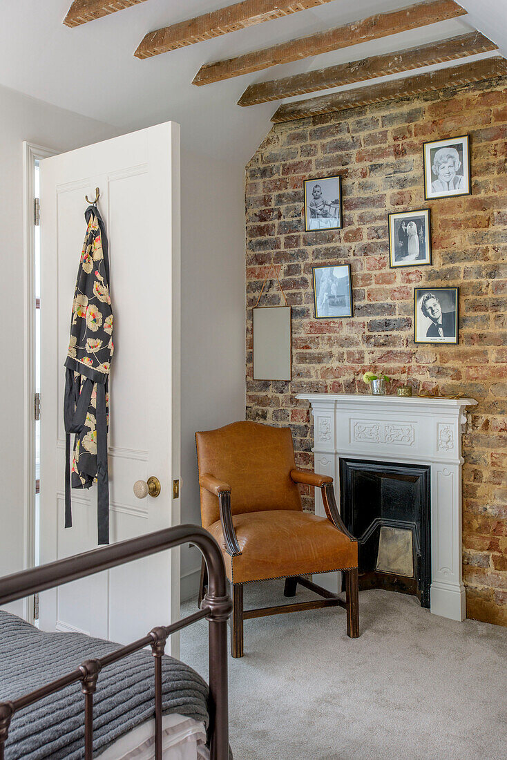 Brown leather armchair at fireside with exposed brick wall in Tunbridge Wells bedroom Kent England UK