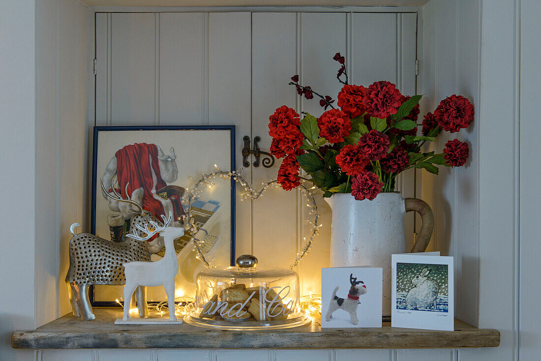 Rentierschmuck und Lichterketten mit roten Blumen und Weihnachtskarten in einem Bauernhaus in Penzance, Cornwall, UK