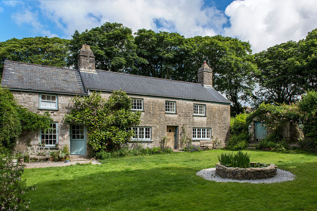 Freistehendes Bauernhaus aus Stein mit Wasserspiel im Rasen in Helston Cornwall UK
