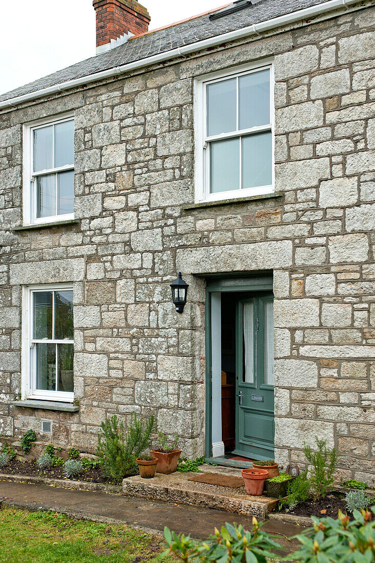 Grüne Eingangstür eines freistehenden Cottage aus Stein in Cornwall, UK