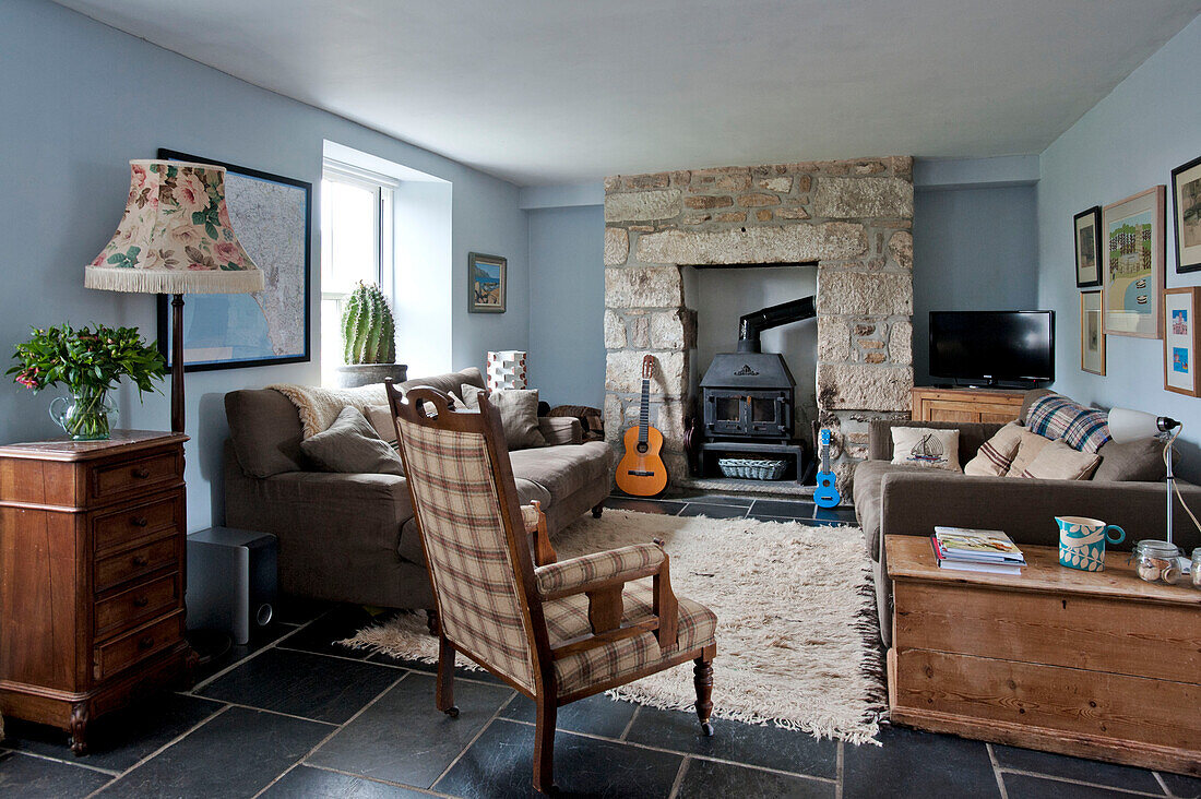 Polstersessel mit freiliegendem Steinkamin im Wohnzimmer eines Ferienhauses in Cornwall England