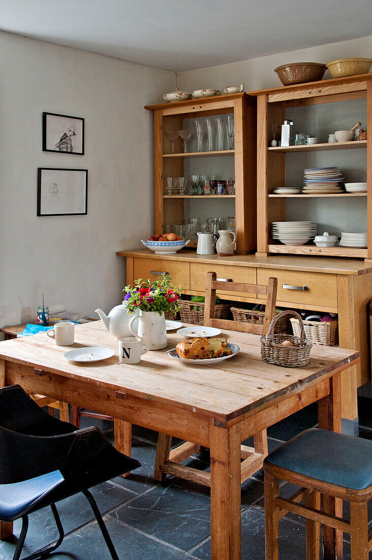 Geschirr auf hölzernem Küchentisch mit Regalkommode in einem Cottage in Cornwall UK