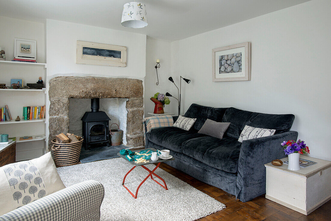 Blaues Zweisitzer-Sofa mit Holzofen im Wohnzimmer eines Cottages in Cornwall, Großbritannien