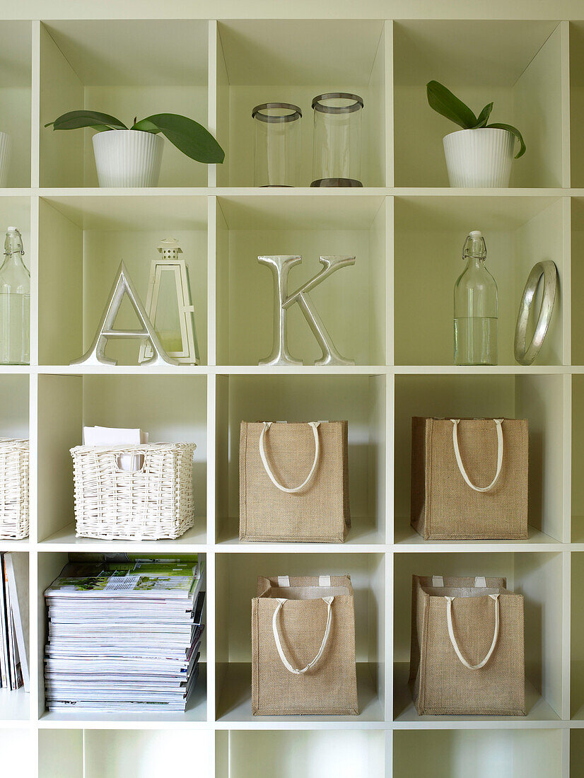 Letters 'A' and ''K' with house plants and hessian bags on shelving unit in UK summerhouse