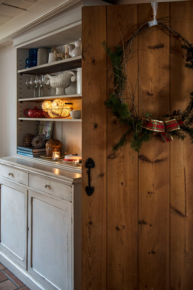 Christmas wreath on wooden door with kitchen dresser in St Erth cottage Cornwall UK