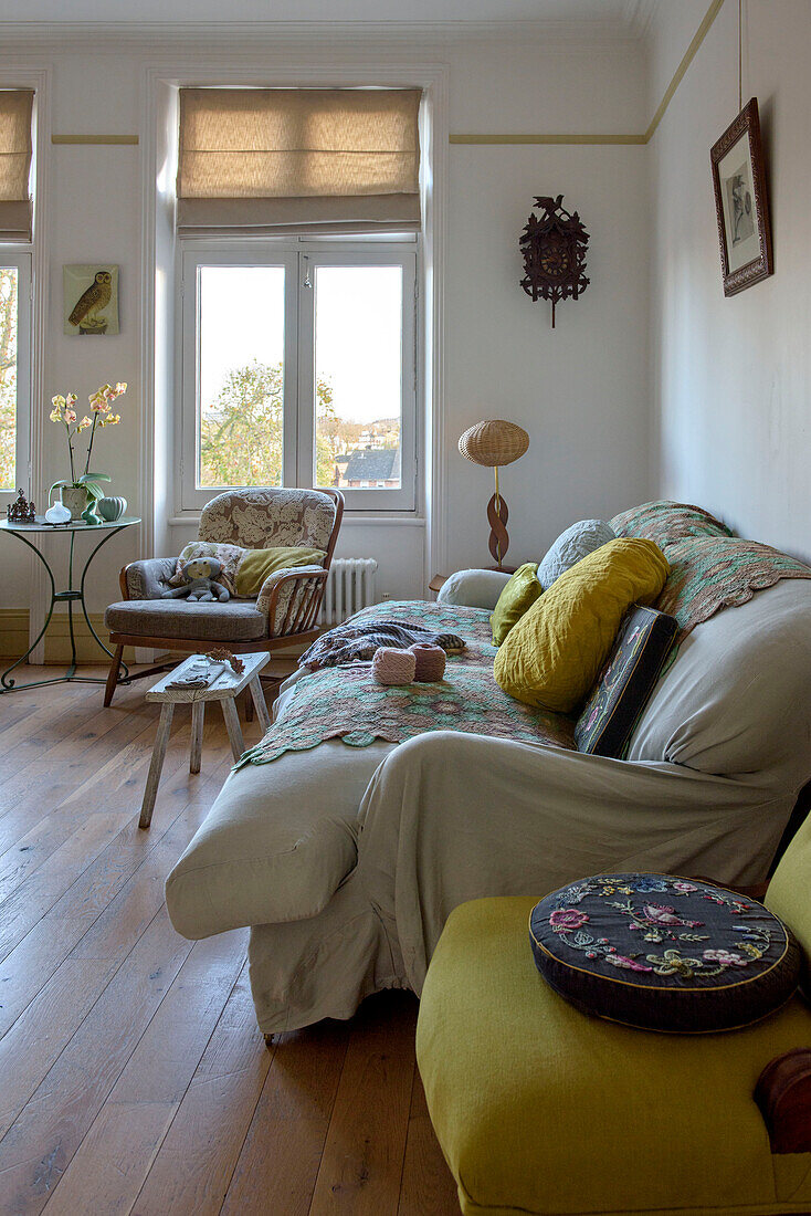 Gobelin-Kissen auf gelbem Stuhl mit cremefarbenem Sofa in einer Wohnung in London UK