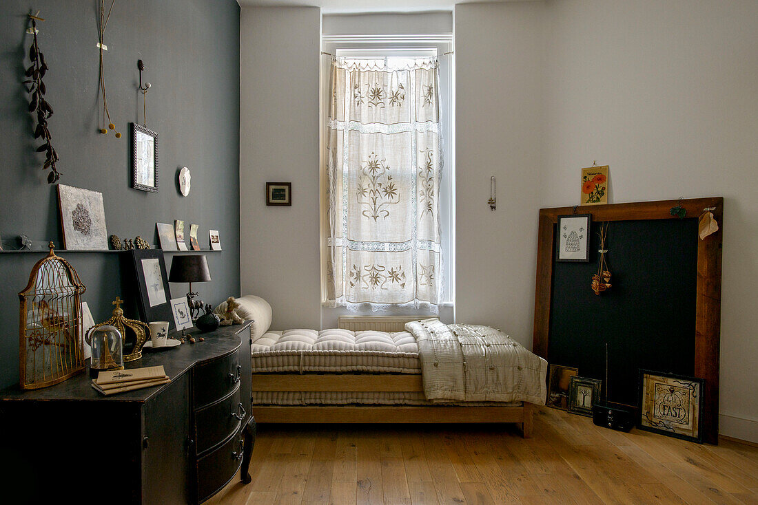 Schwarzes Sideboard und Einzelbett mit bestickten Gardinen in einem Londoner Haus UK