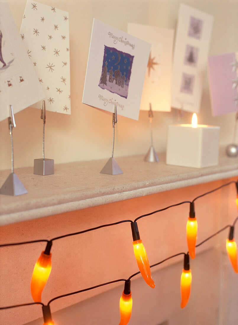 Weihnachtskarten auf einem Kaminsims mit Lichterketten