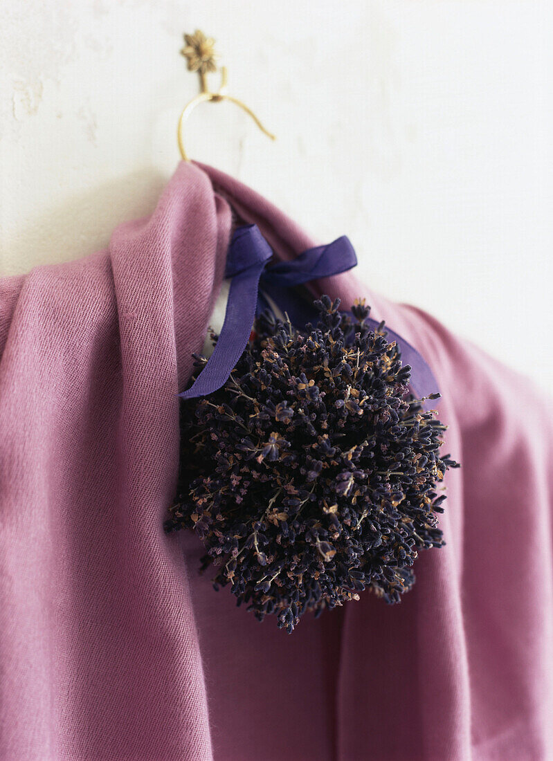 Rosa Strickjacke auf dem Handgelenk mit einem Ball aus getrockneten Lavendelblüten
