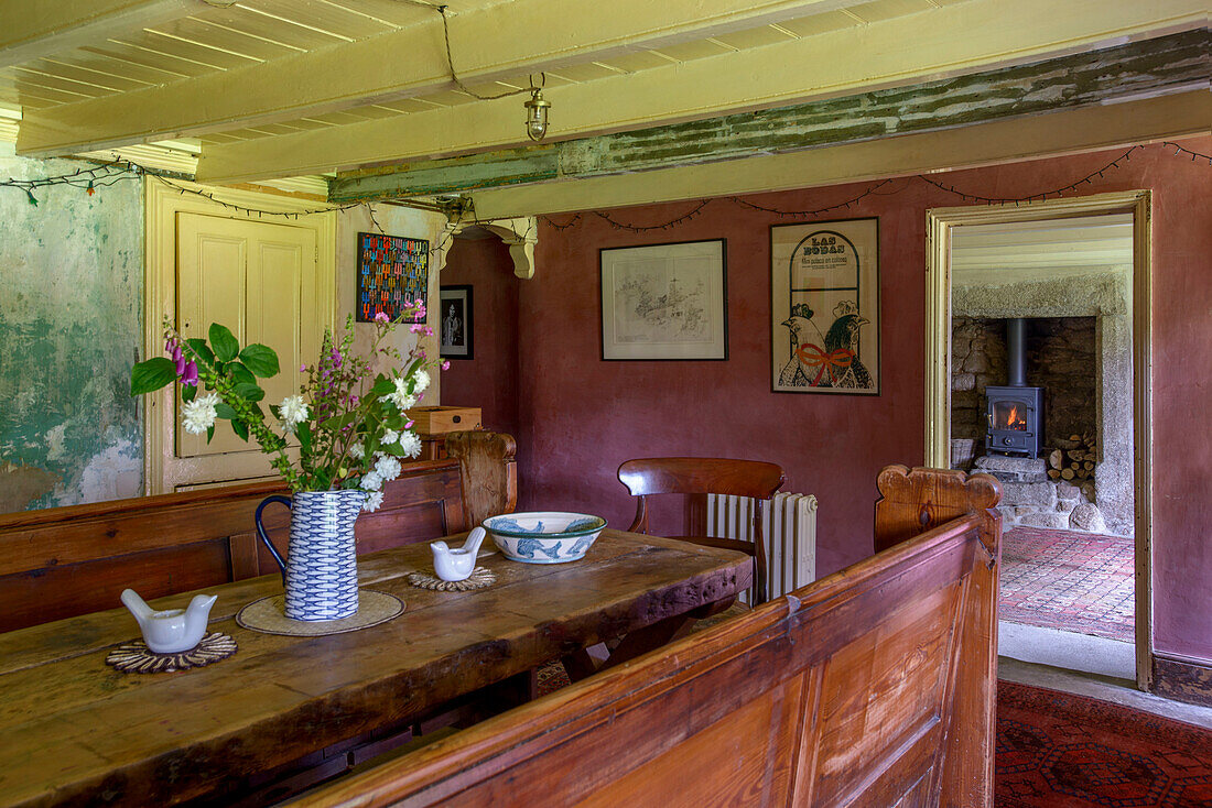 Altmodische Sitzbank und Tisch aus Holz mit Blick durch die Tür in einem Bauernhaus in Helston, Cornwall UK