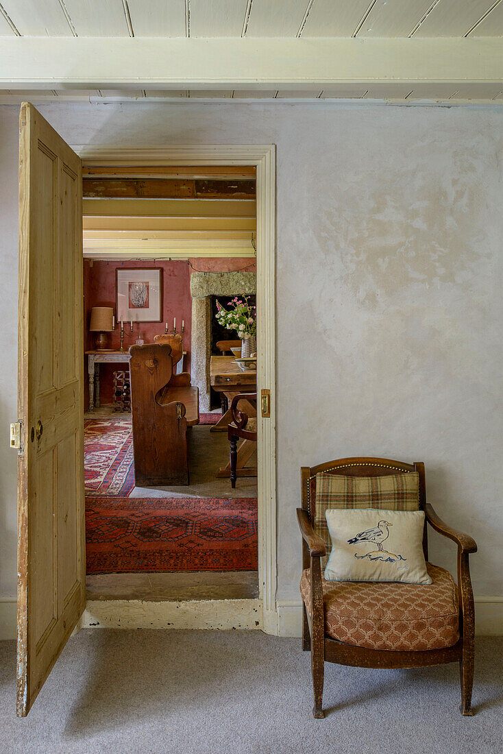 Kleiner Sessel mit Blick durch die Türöffnung in einem Bauernhaus in Helston, Cornwall UK