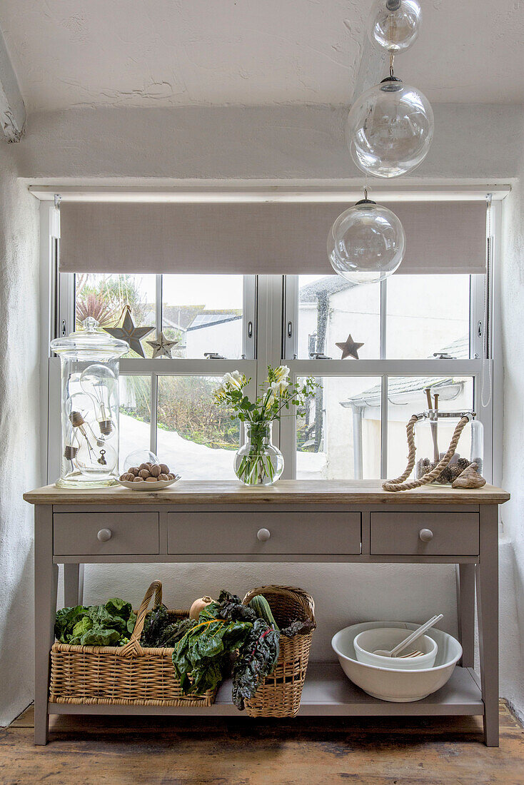 Glass ornaments hang above console table with stars in window of Marazion beach house Cornwall UK