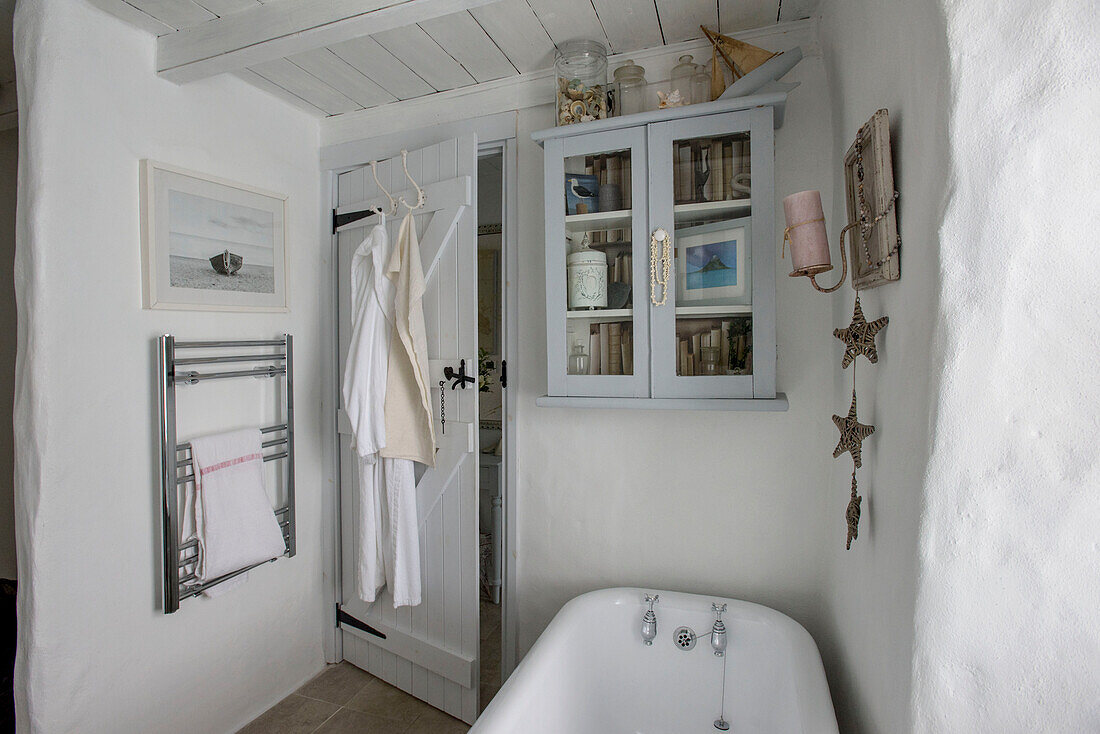 Glasvitrine über der freistehenden Badewanne mit Handtuchhalter in Marazion beach house Cornwall UK
