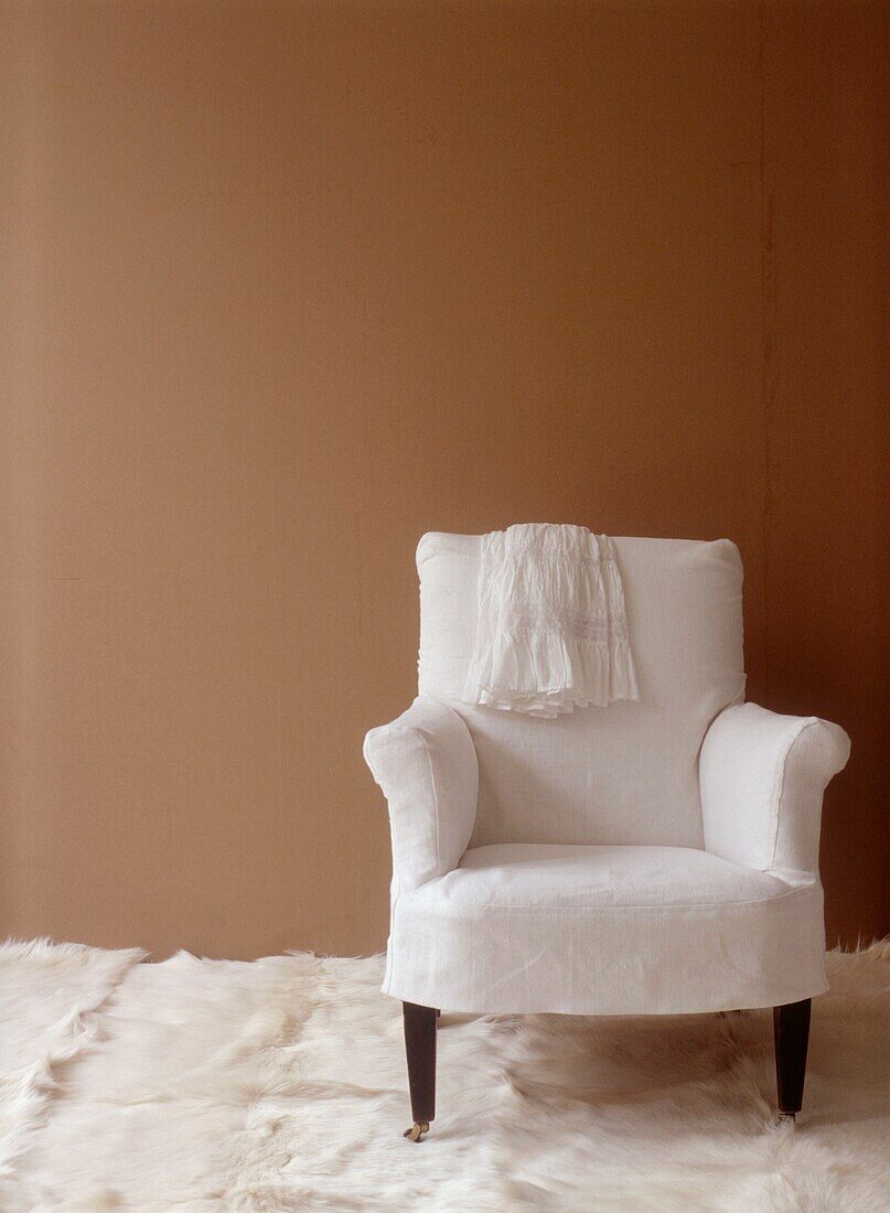 Budget-Style-Zimmer aus der Nähe mit Vintage-Sessel, bezogen mit recyceltem Leinen und brauner Papiertapete