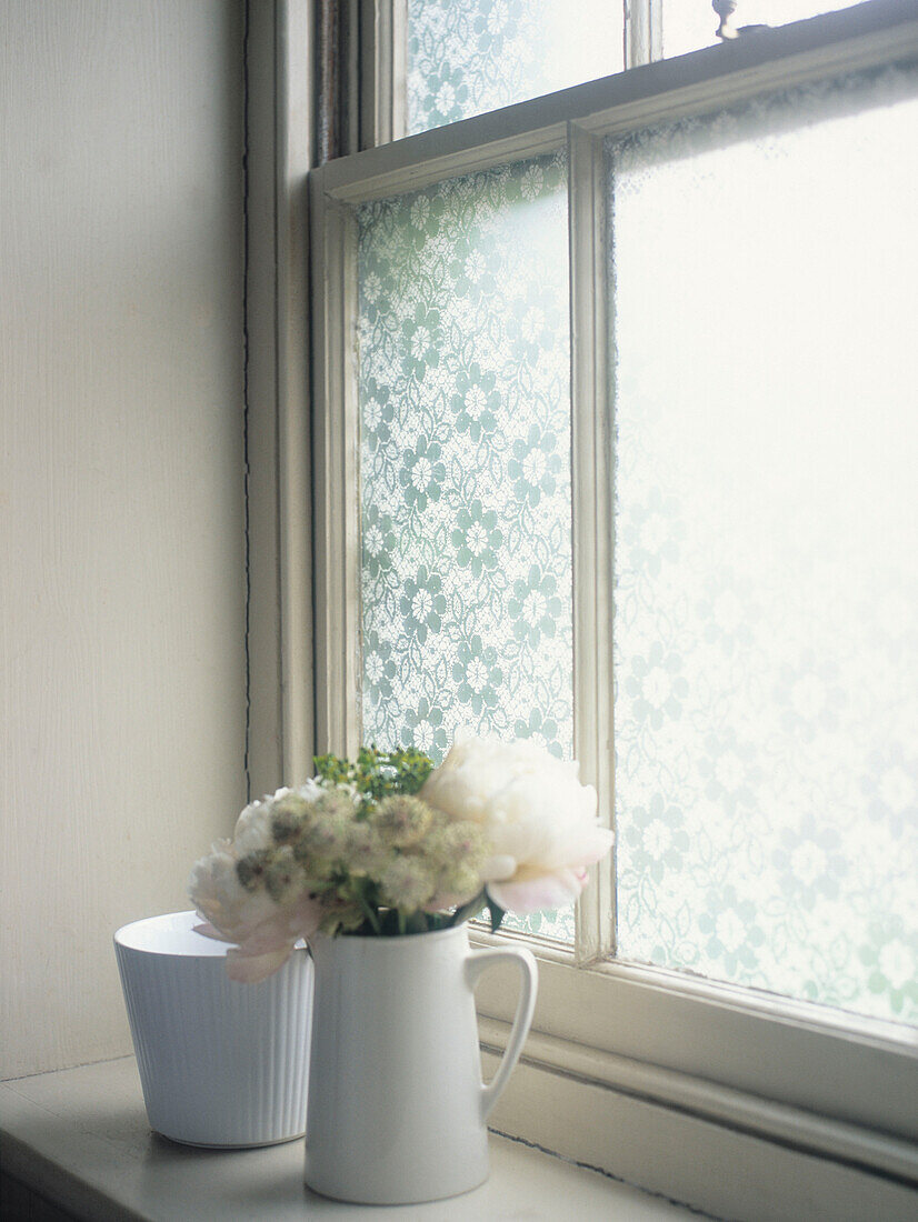 Cut flowers on windowsill with frosted glass