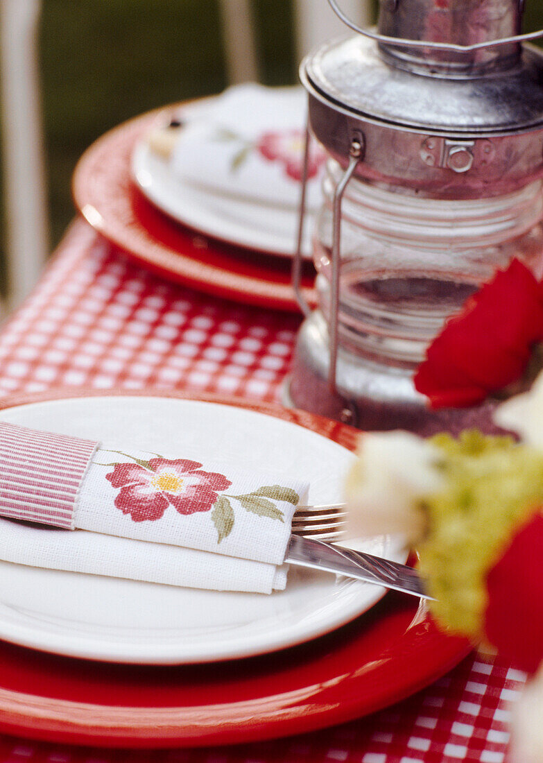 Close up of red and white tableware set on a table in the garden