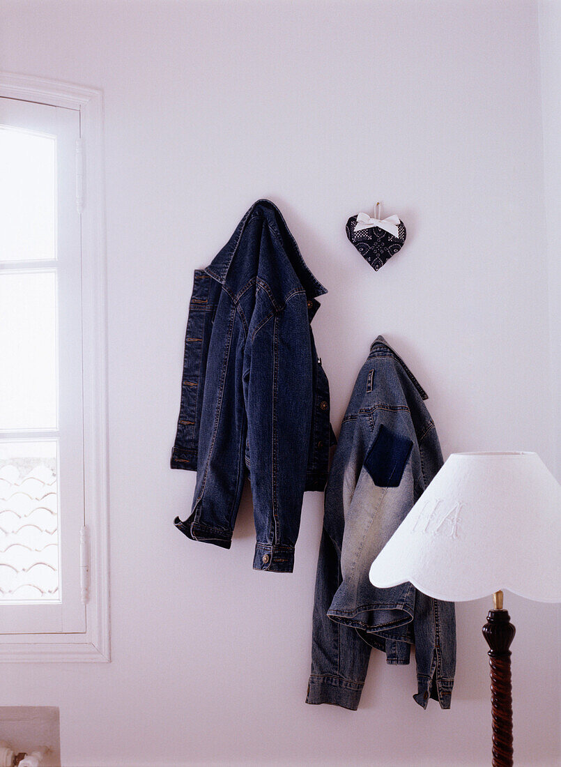 Zwei Jeansjacken, die an der Wand hängen